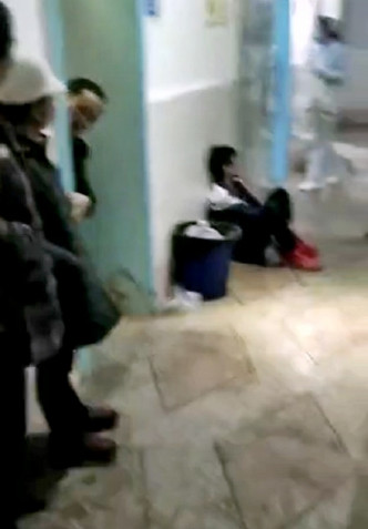 一名身穿校服的学生蹲坐在走廊边，双手有血迹。
