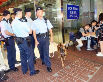 警员在大厦地下摆放张枱，登记出入人士身分，并派出警犬协助截查可疑人士。