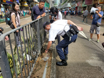 警員正撿起遺留花槽內的頭盔風鏡。