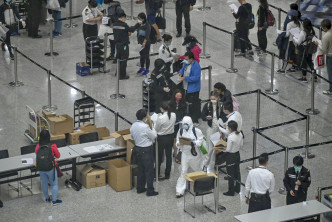 政府實施除中國以外地區入境人士需強制檢疫，入境處及機場人員替抵港人士戴上追蹤手帶。  資料圖片