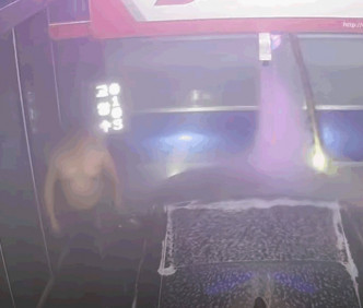半裸上身的男子於自動洗車機區域內四處走動。影片截圖