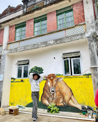 郑融与客家村上别贝特色的壁画合照。