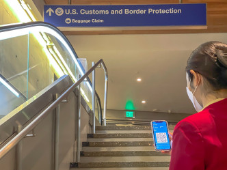 旅客抵达洛杉矶国际机场后，向当地职员出示其数码健康通行证。