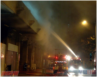 浓烟包围整个街市，消防射水灌救。资料图片