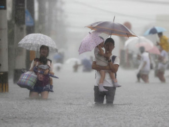 福岡縣久留米市嚴重水浸市民要涉水而行。AP