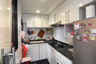 廚房沿牆身訂造廚櫃，旁邊置有雪櫃。