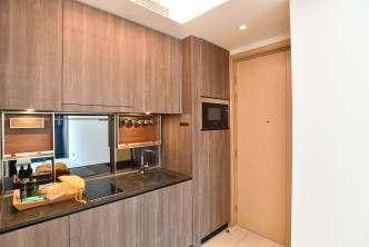 開放式廚房位於客廳一隅，設有廚櫃、微波爐等所需配備。