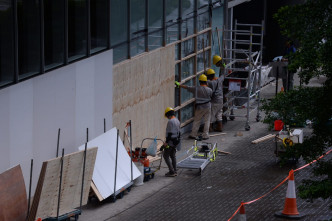 工人以木板圍封被打爆及塗鴉的玻璃，進行維修。