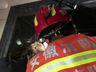 消防员小心护着幼童头部，为他解困。(网图)