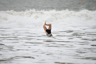 泳客趁风暴吹袭下滑浪冲浪。