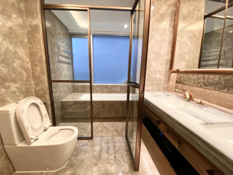 浴室以雲石飾面，玻璃浴屏更以金屬鑲邊，盡顯精緻。