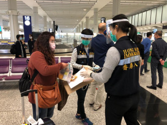入境处人员在香港机场为乘坐包机的港人送上由航空公司提供的食物包。
