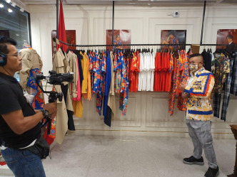 身處時裝店內，介紹泰國喺疫情下，設計師設計咗特色口罩嚟襯衫。
