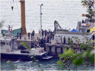 尸体由警员抬上码头。