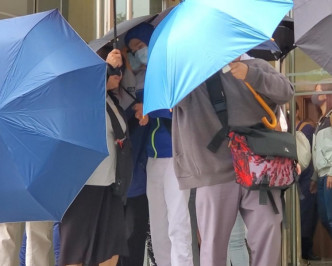 被告羅敏聰（左3）被傘陣護送離開法院。陳楚琨攝