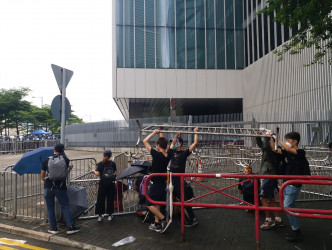 示威者拿起路旁的鐵架，放置在公路上阻塞立法會出入口。