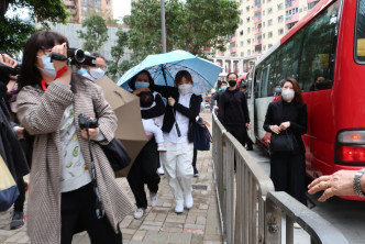郭富城的两名女儿由工人姐姐抱着，并在人墙和伞阵遮掩下离开。