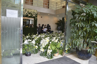 殯儀館的地面大堂牆上以白玫瑰及綠色植物作佈置。