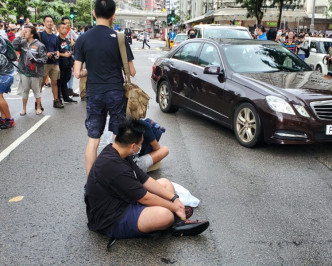 其中3名男子走出马路坐在路中心。杨伟亨摄