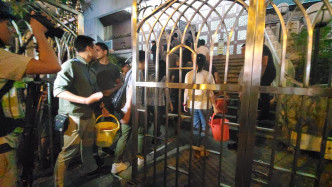 警方攜水桶進入寺內。