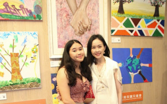 背後的雙手緊繫畫作，正是周瑋瑩女兒為兒童會籌得20多萬元的作品。