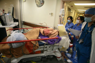 男伤者在玛丽医院急症室抢救后，由医护人员推上病房。