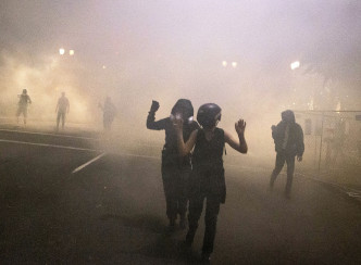 示威者在逃离催泪烟。 AP