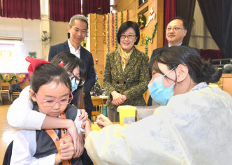 陳漢儀（後排中）與黃加慶（後排左）到訪保良局陳守仁小學，視察外展疫苗接種活動。