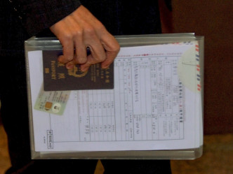 他手持透明公文袋内有一叠文件，包括写有香港圣公会教省办事处的信封、特区护照、陈同佳的香港身分证及入台签证申请书。