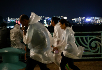 红磡码头有市民穿上雨衣追风。