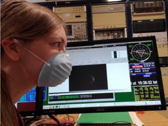 戴著口罩工作的科学家与小行星相映成趣。网图