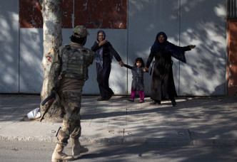 惊慌的民众在塔利班战士指示下离开现场。美联社图片