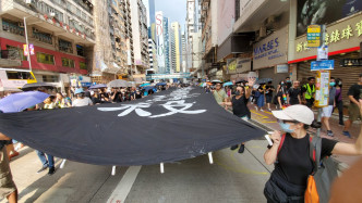 示威者拉起黑底白字的巨型直幡，沿途高喊口号。