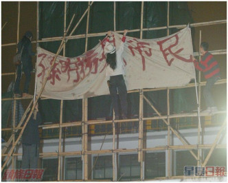 示威者攀上地盤棚架,掛上反對拆卸的橫額。資料圖片