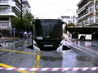 雅典有马路路陷，导致一辆巴士被困。AP图