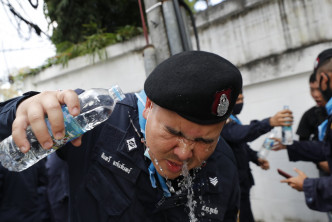 「中招」警员以清水洗眼。AP
