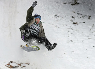 有人苦中作乐在雪地上玩滑雪板。AP图片