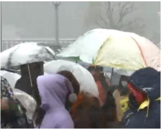 市民打开雨伞挡雪。NHK