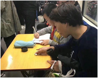 女子自備摺枱在地鐵車廂裡展開埋首做功課。