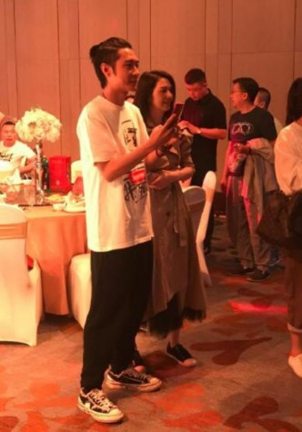 張丹峰在婚安宴上不時用手提電話拍攝，期間洪欣在旁站着。