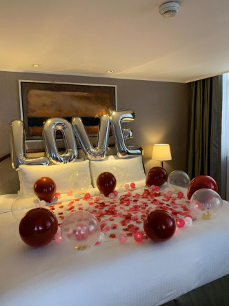 酒店职员悉心布置两人房间，连床铺都有红白气球加玫瑰花瓣，床头有大大个LOVE字。