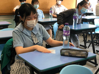 有学生进入课室后，用湿纸巾清洁桌椅及用品。
