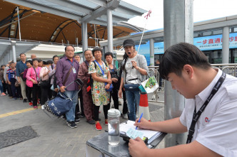 旅檢大樓外有大批旅客排隊上車。郭顯熙攝