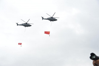 悬挂国旗及区旗的飞行服务队直升机飞越维港上空。