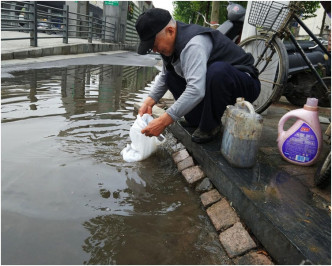 王伯每逢雨后都蹲在路边用胶袋收集路边的积水。