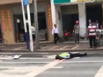 交通警员面部朝下趴在马路上，身上和地上有血迹。