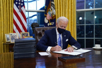拜登上任首天坐在白宫随圆形办公室「坚毅桌」前开始工作。AP