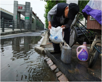 用胶袋收集路边的积水再倒入胶桶内。