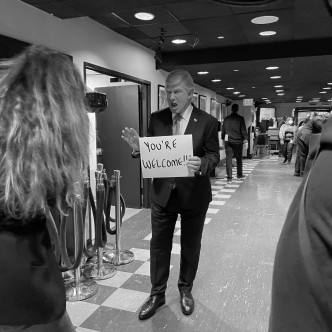 艾力寶雲上載扮成特朗普並舉着「YOU'RE WELCOME」紙牌的黑白照。