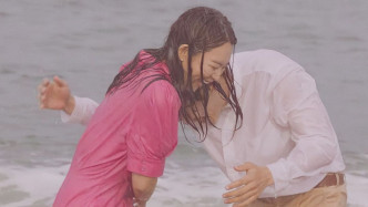 二人在沙滩淋雨嬉戏。